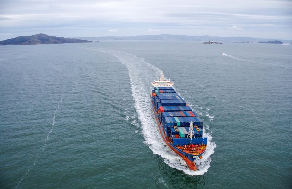 Aerial view of a large container ship sailing through open ocean waters.