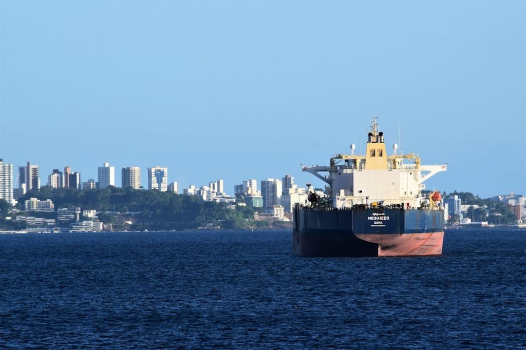 A cargo ship anchored in Salvador, Brazils harbor with the city skyline in the backdrop.